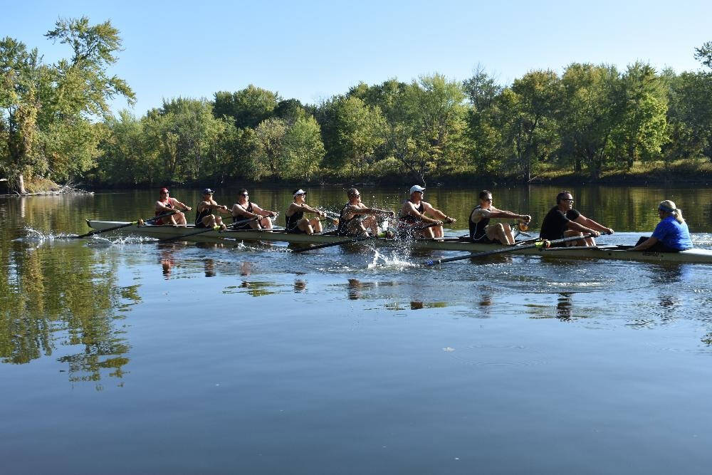 9 people rowing on a lake on a clear day